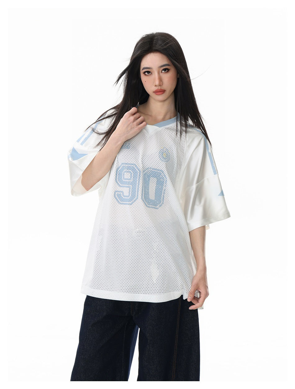 Close-up of a model in the white mesh jersey tee with blue '90' print and satin-like raglan sleeves, with dark jeans