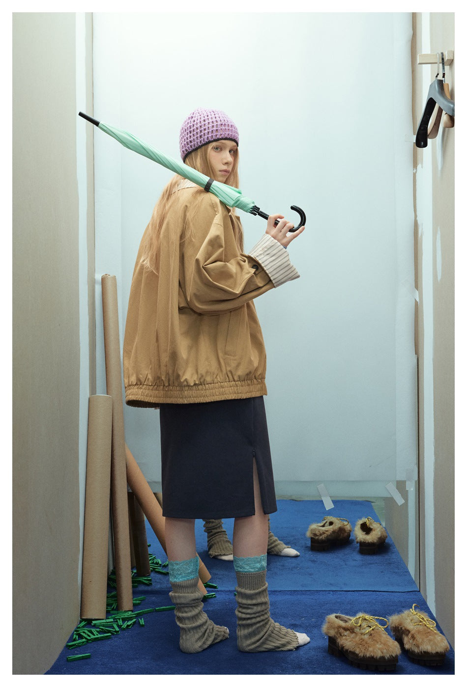 Model shows the back and side of a tan jacket with a gathered hem and striped cuffs.