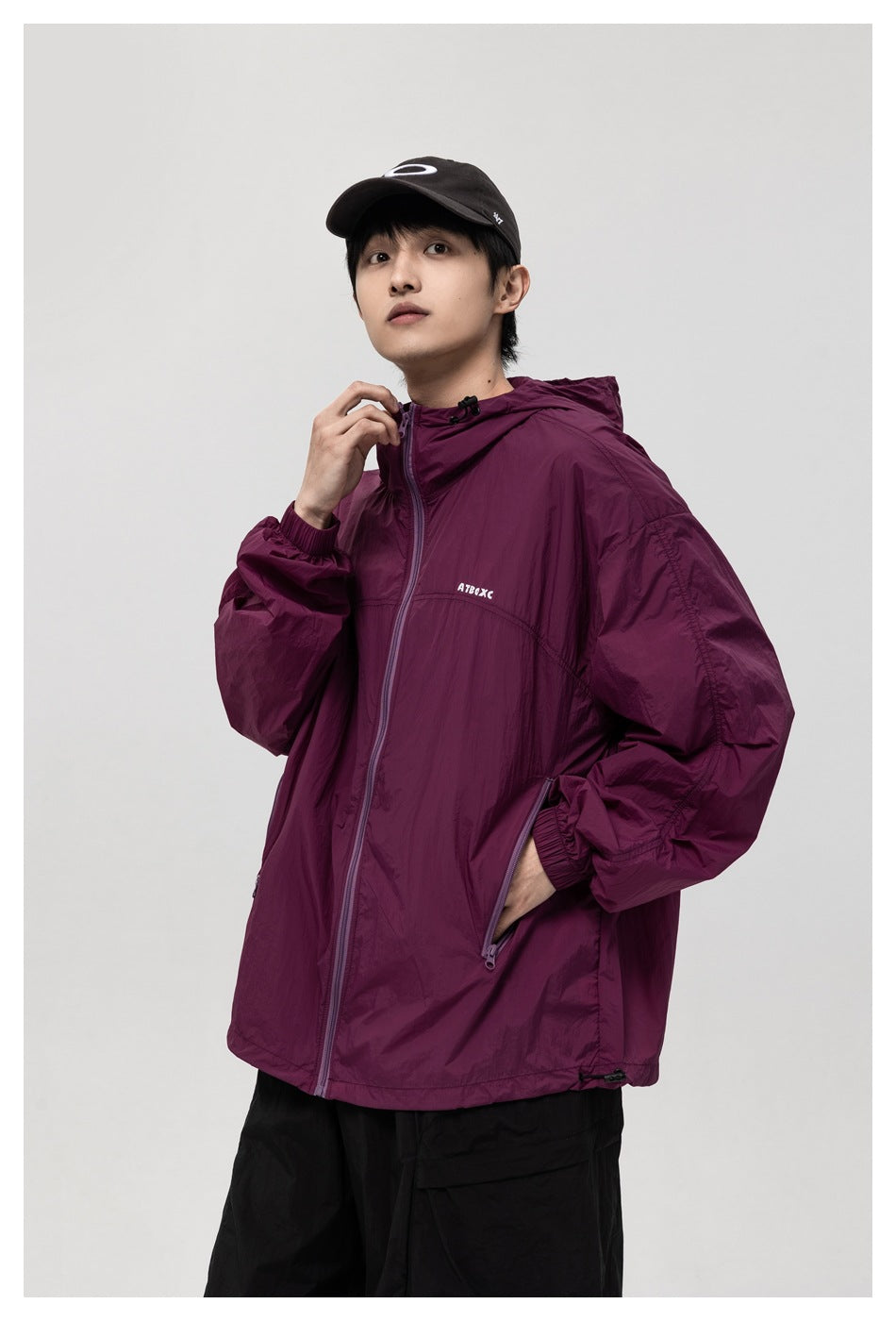 Model wearing a plum hooded jacket with a front zipper and angled pockets, shown from the front.