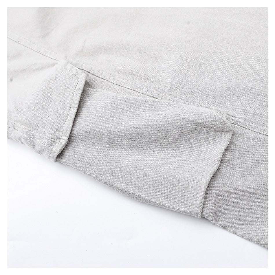Close-up of a light gray garment showing a folded pocket edge and stitched seams.