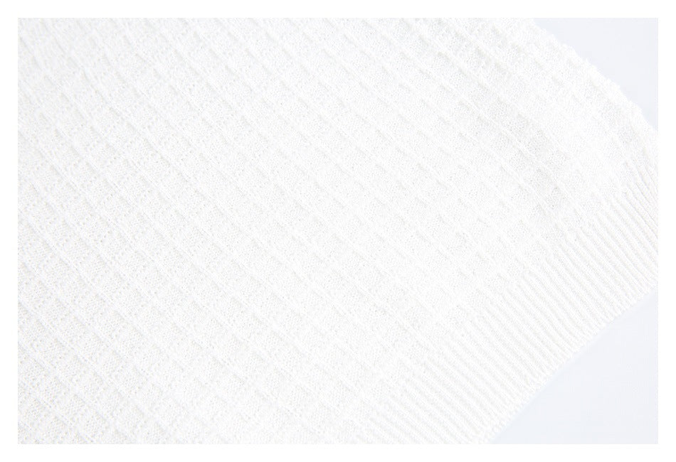 Close-up of white textured knit and a wide ribbed edge.