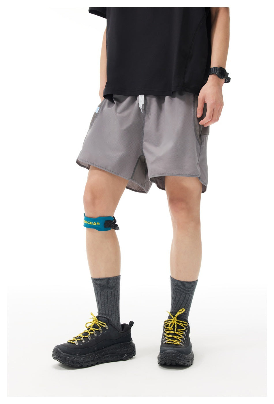 Three-quarter view of a model wearing loose gray drawstring shorts with layered hems.