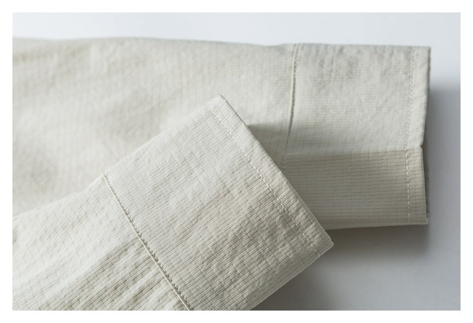 Close-up of stitched cuffs and seams on light beige ribbed garment fabric.