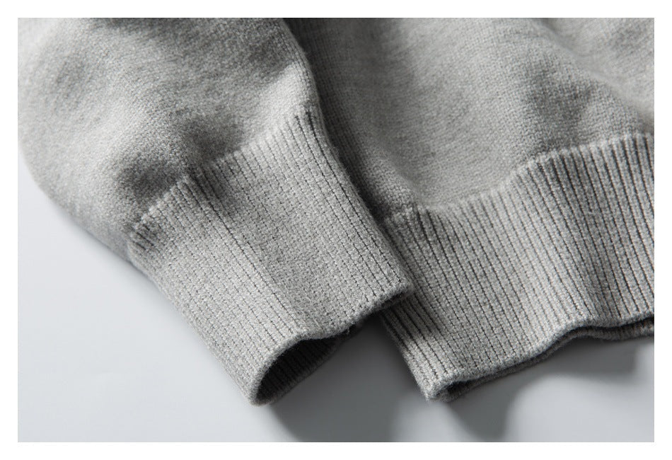 Close-up of a light gray knit sweater showing a ribbed sleeve cuff and hem.