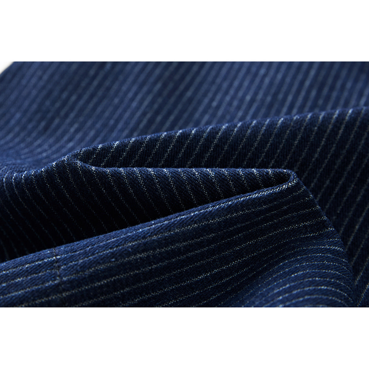Close-up of folded navy fabric with fine light pinstripes and visible stitching.