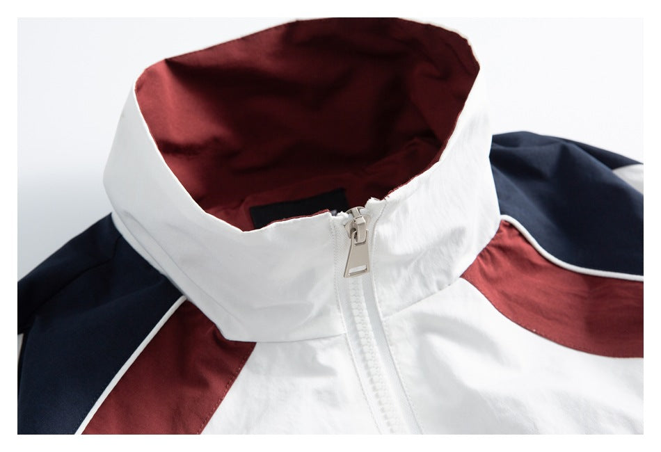 Close-up of a white track jacket collar with burgundy lining, navy shoulder panels and a front zipper.