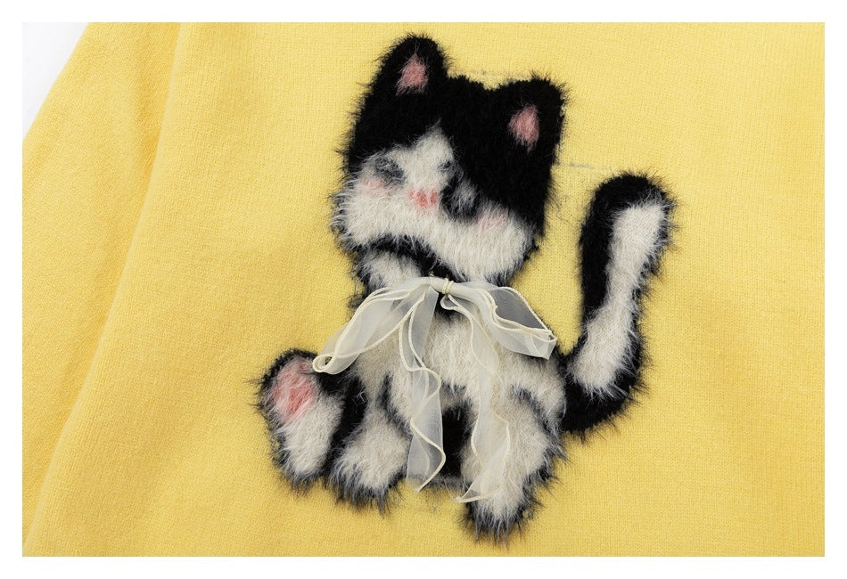 Fuzzy black-and-white cat appliqué with pink accents and a sheer cream bow on the pale yellow sweater.