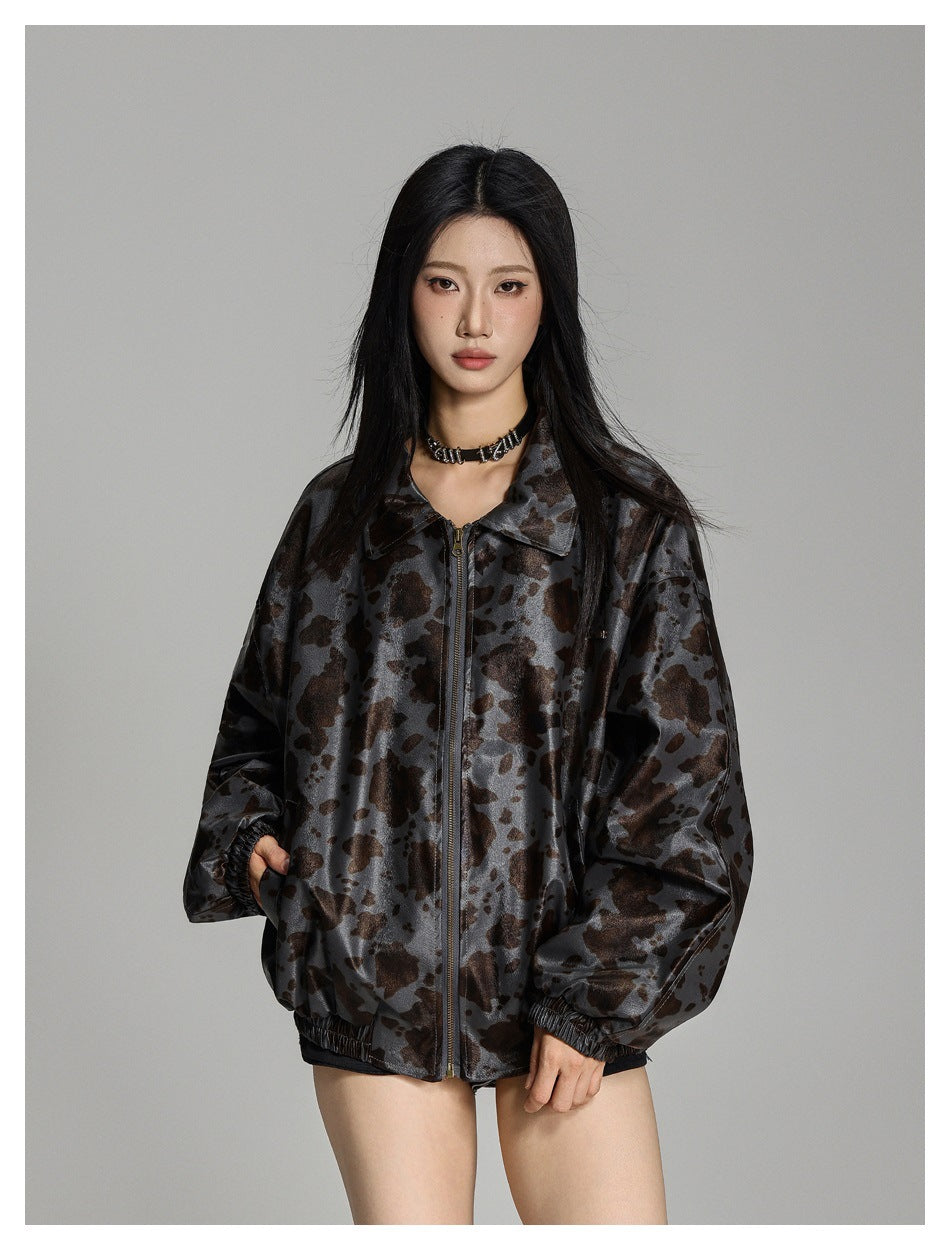 Model wearing an oversized charcoal-gray and brown spotted jacket with a pointed collar, front zipper, and elastic cuffs.