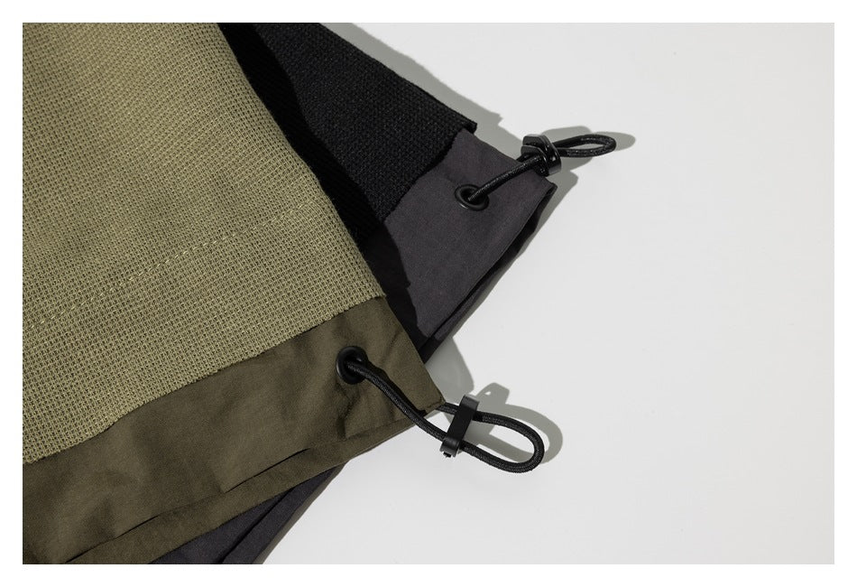 Close-up of olive-khaki and charcoal garment hems with black elastic drawcords and toggles.