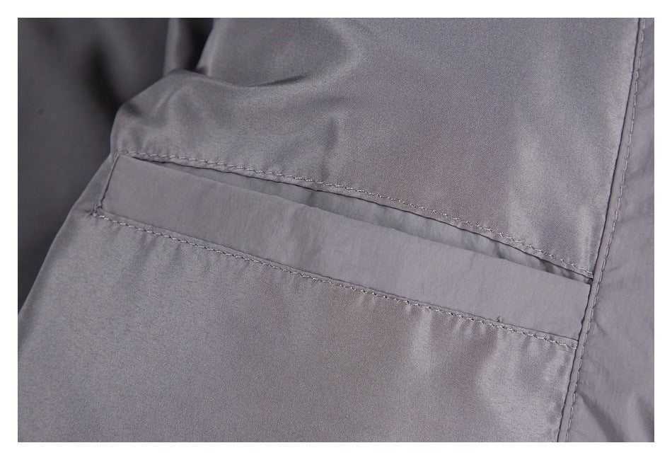 Close-up of a stitched rectangular pocket opening on gray jacket fabric.