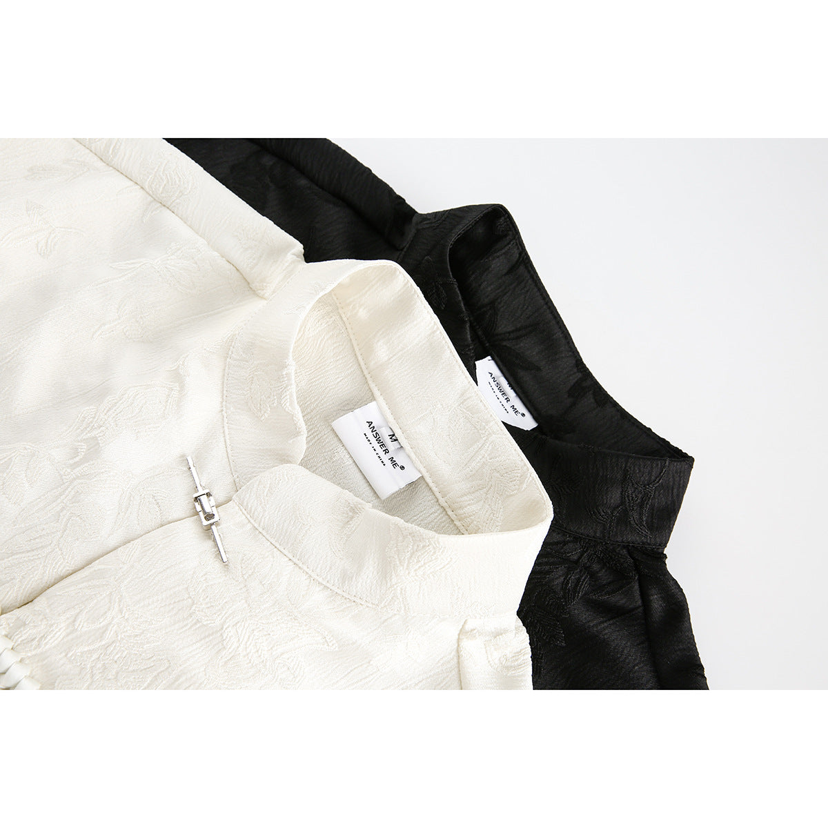 Close-up of ivory and black shirt collars with floral patterns and metal clasp closures.