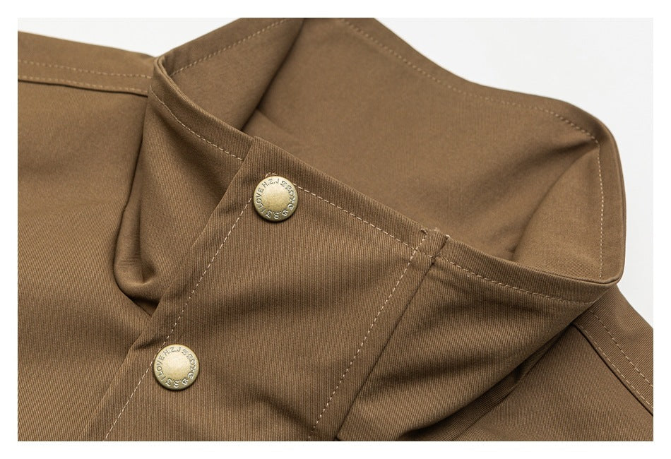 Close-up of a brown garment with stitched panels and two round metal snap buttons.