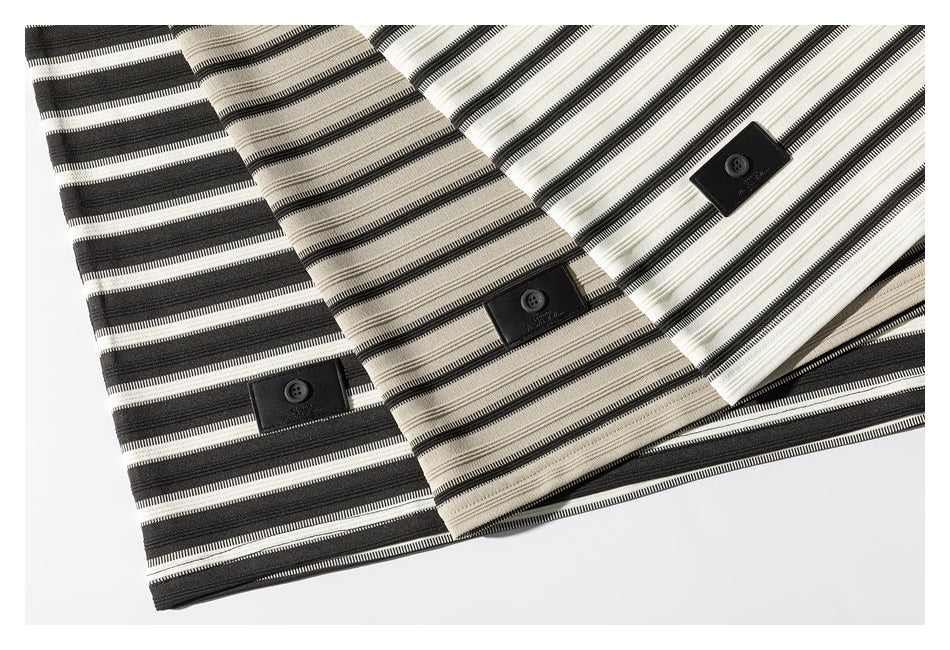 Three overlapping striped garment panels in black, beige, and white, each with a black button tab.
