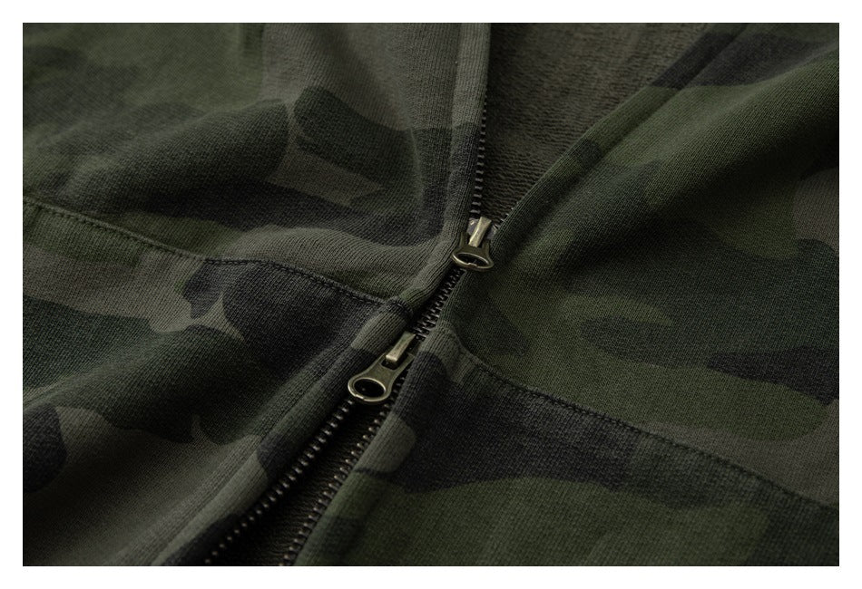 Close-up of a dark green camouflage garment with a black two-way zipper.
