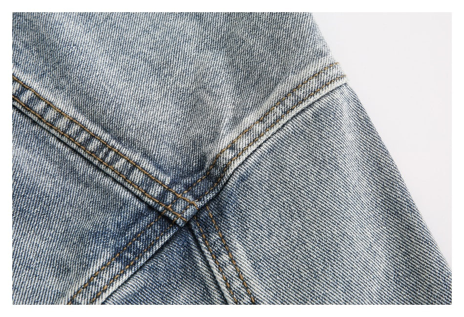 Close-up of intersecting double-stitched seams on faded blue denim.