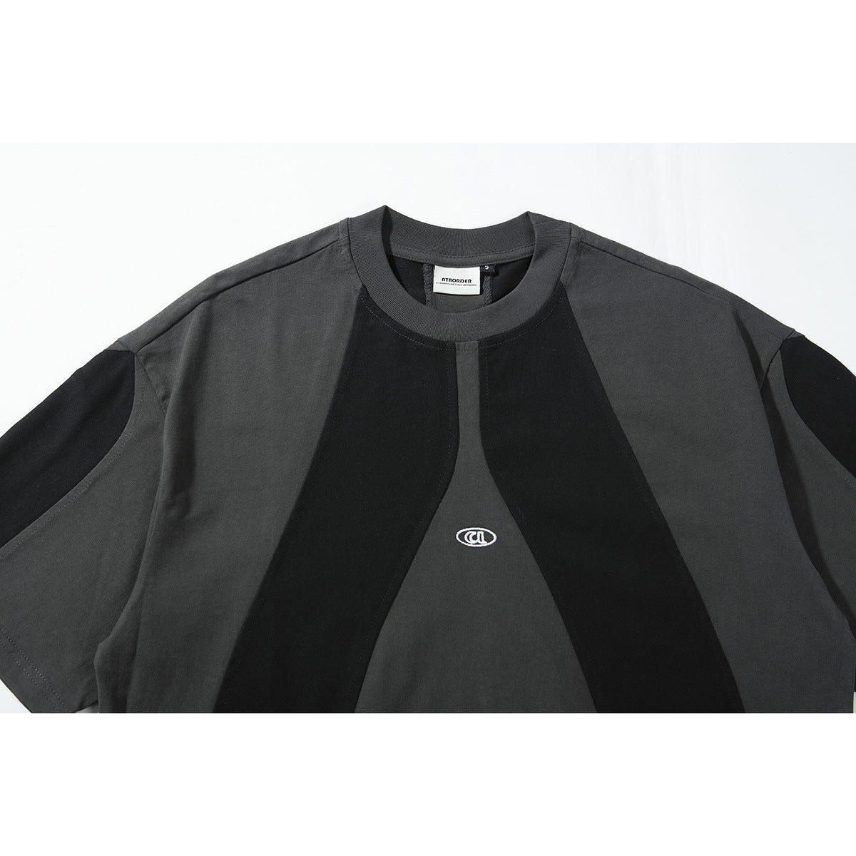 Close view of a charcoal and black color-block short-sleeve T-shirt with a small white chest emblem.