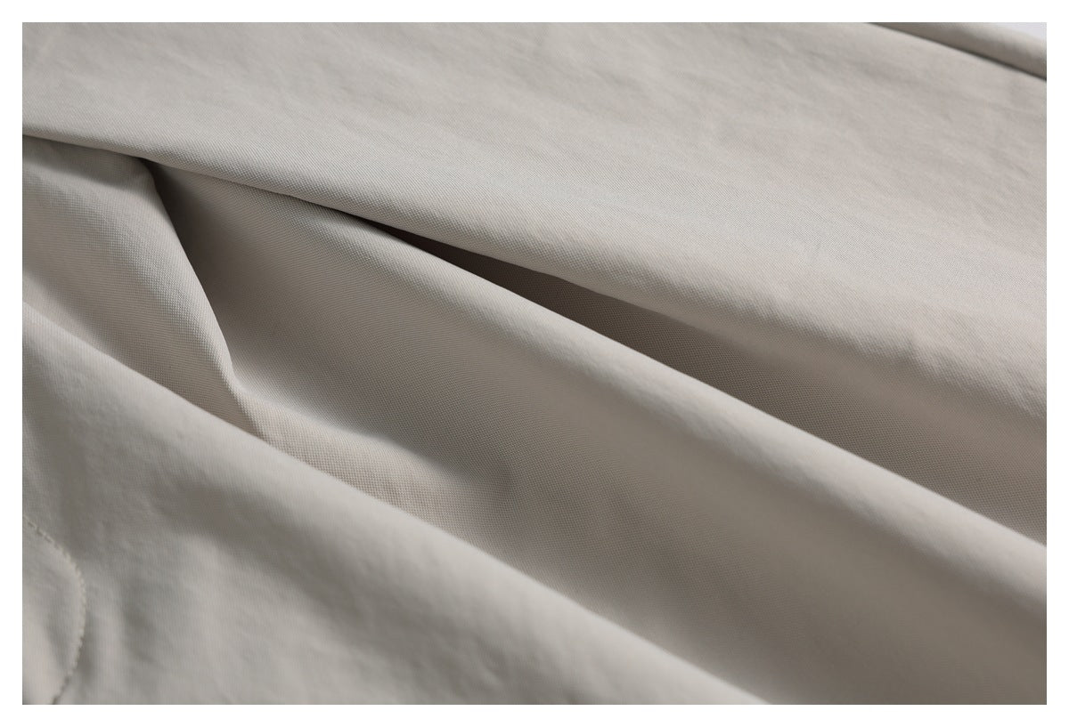 Close-up of the light taupe garment's softly folded fabric and subtle woven texture.