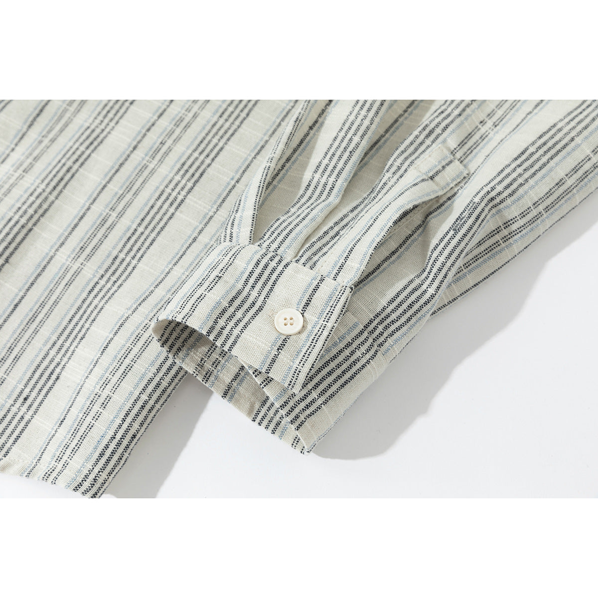 Close-up of the ivory shirt's striped cuff and white button.