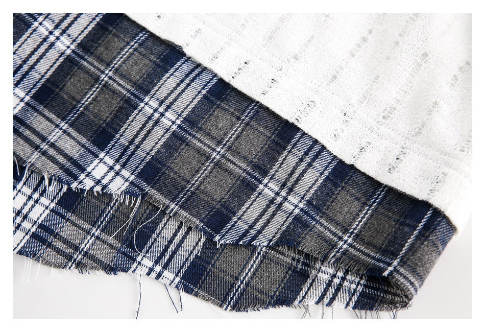 Close-up of white open-knit fabric meeting a navy and gray plaid panel with a frayed edge.