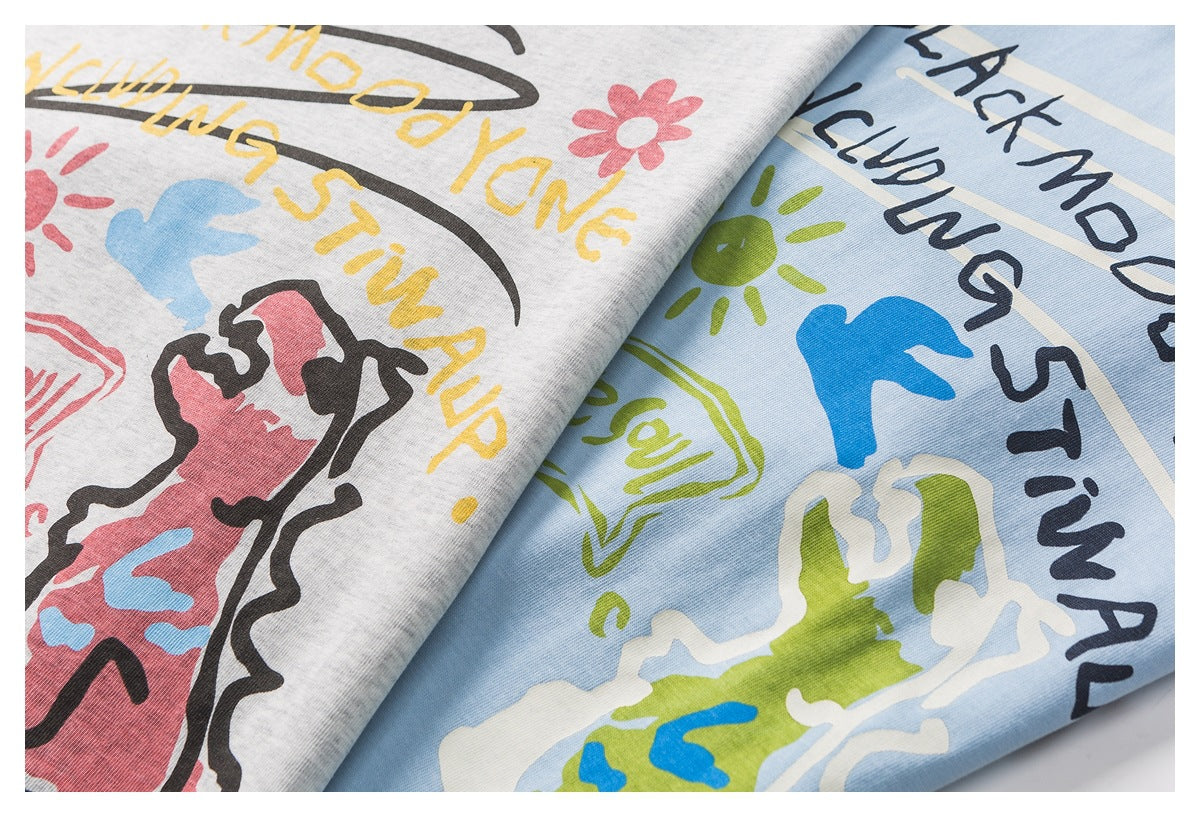 Close-up of two light gray and pale blue shirt colorways with colorful graphic prints and English lettering.