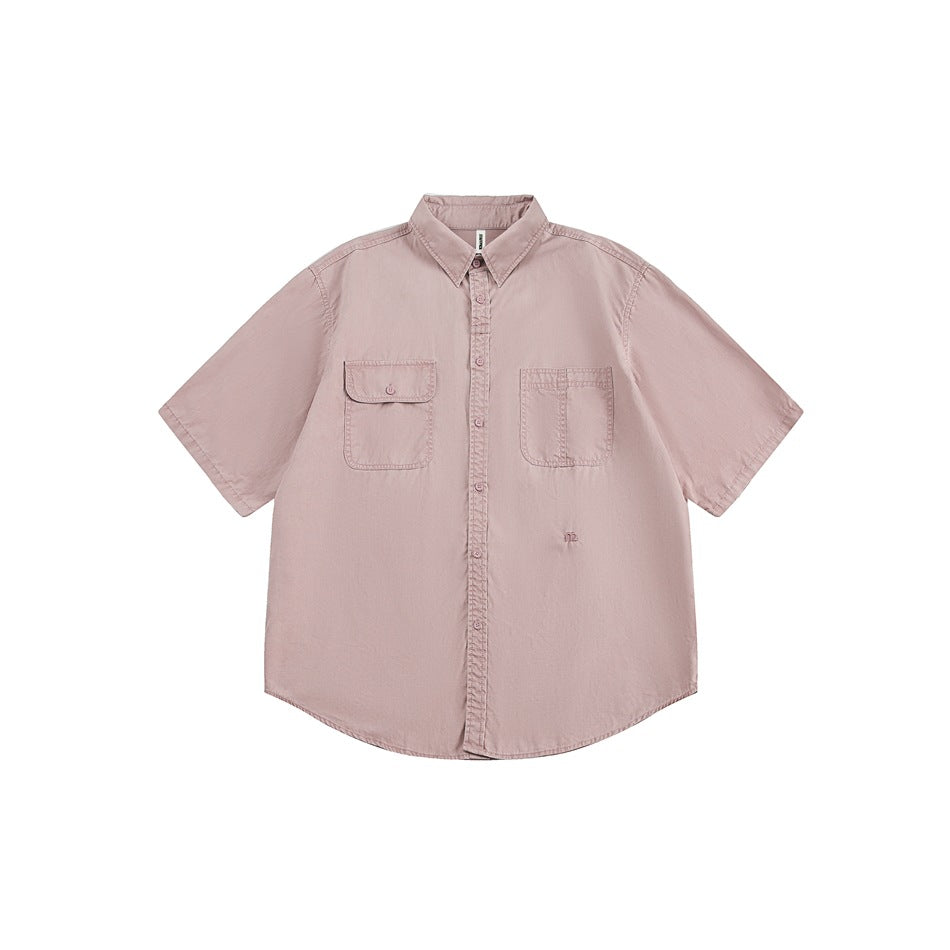 Front view of a dusty pink short-sleeve button-up shirt with a collar and two chest pockets on white.