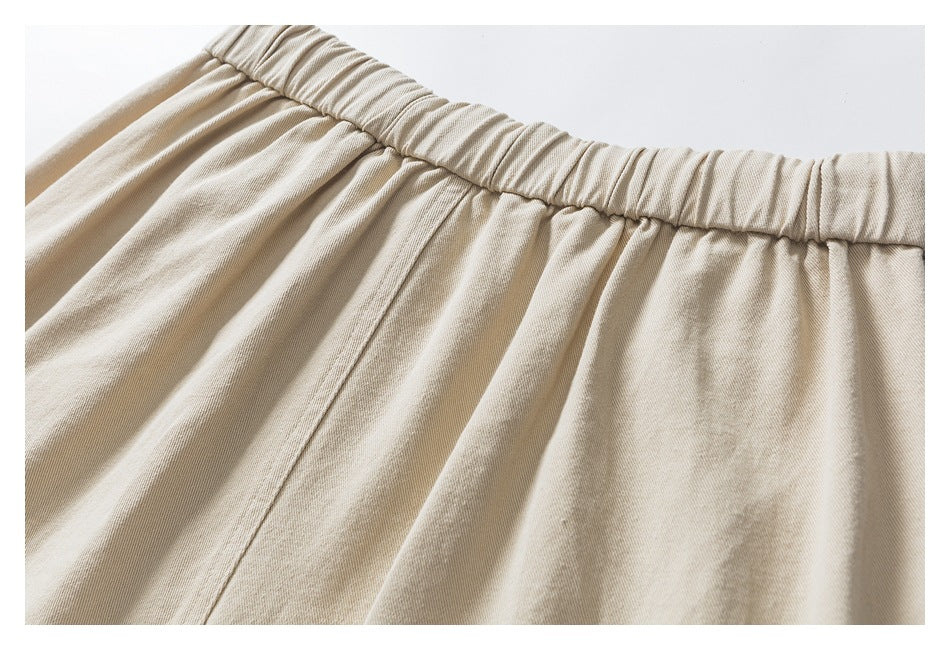 Close-up of the gathered elastic waistband and back seam on beige pants.
