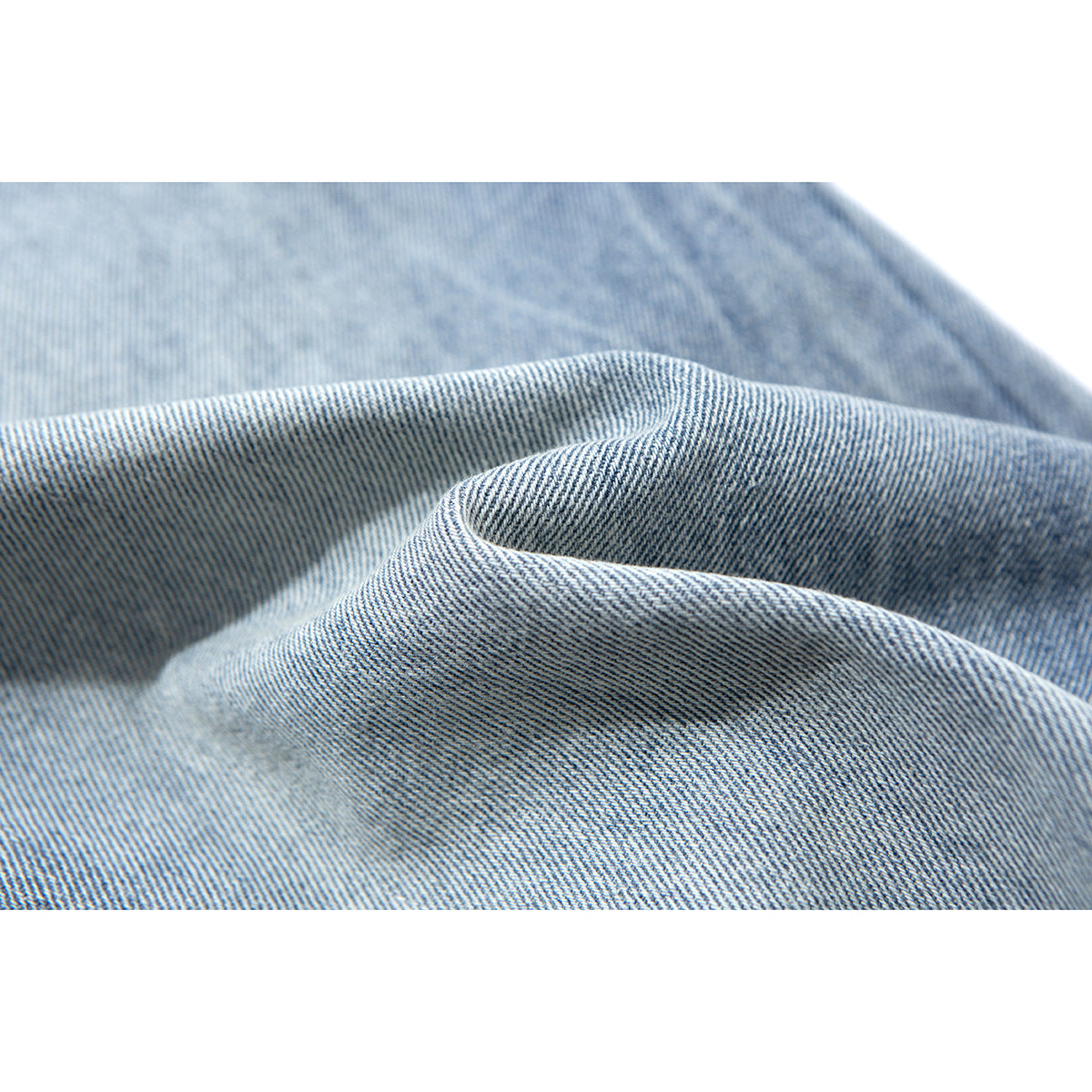 Close-up of folded light blue denim showing its diagonal weave and texture.