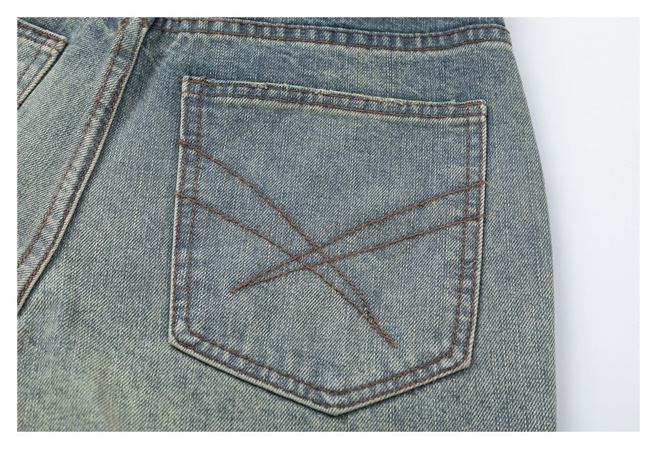 Close-up of a rear pocket on faded blue jeans, with angular reddish-brown stitching.