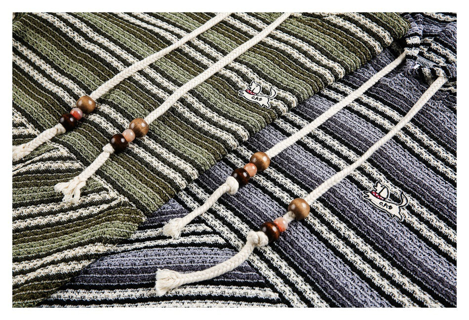 Close-up of striped pullover fabric, cream braided drawstrings with wooden beads, and small animal patches.
