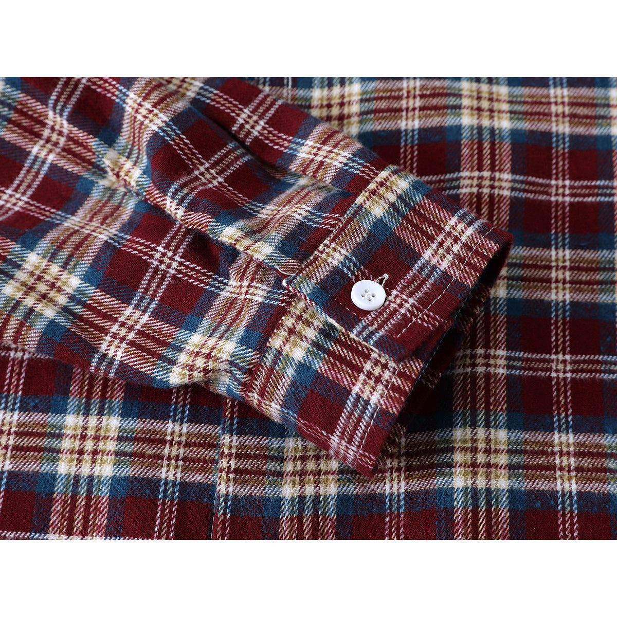 Close-up of a buttoned cuff on a burgundy, navy, cream and tan plaid shirt.