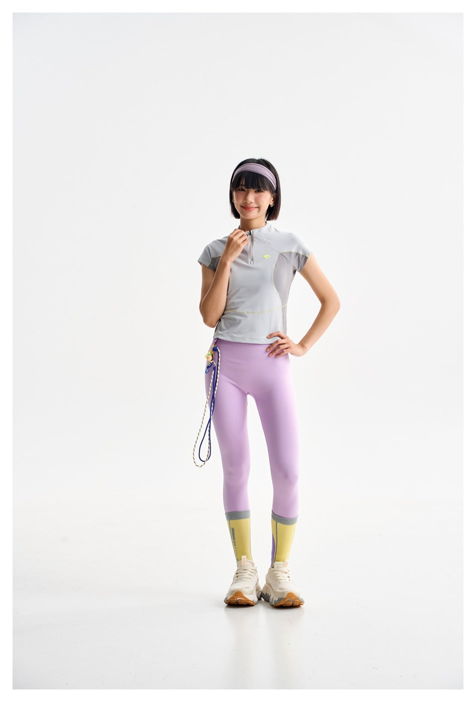 Model in a light gray short-sleeve quarter-zip top, lilac leggings, and yellow color-block socks.