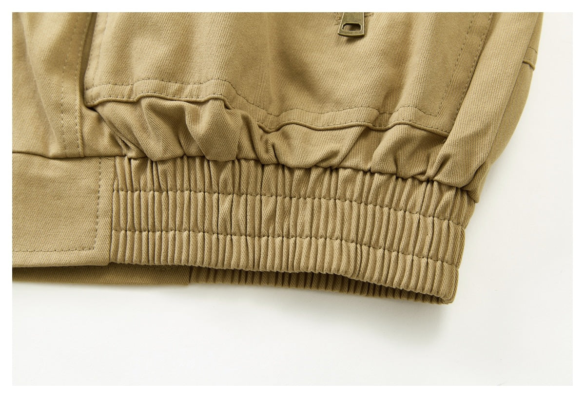 Close-up of the tan jacket's gathered, elasticized waistband and stitched hem.