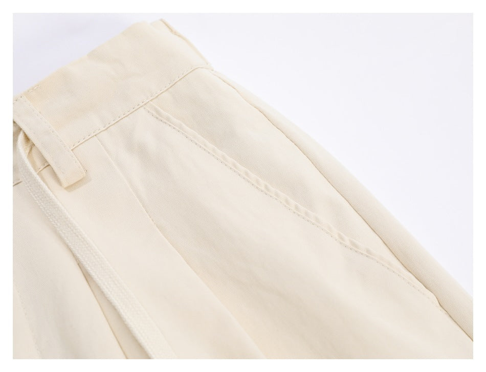 Close-up of cream trousers showing the waistband, belt loop, and slanted front pocket.
