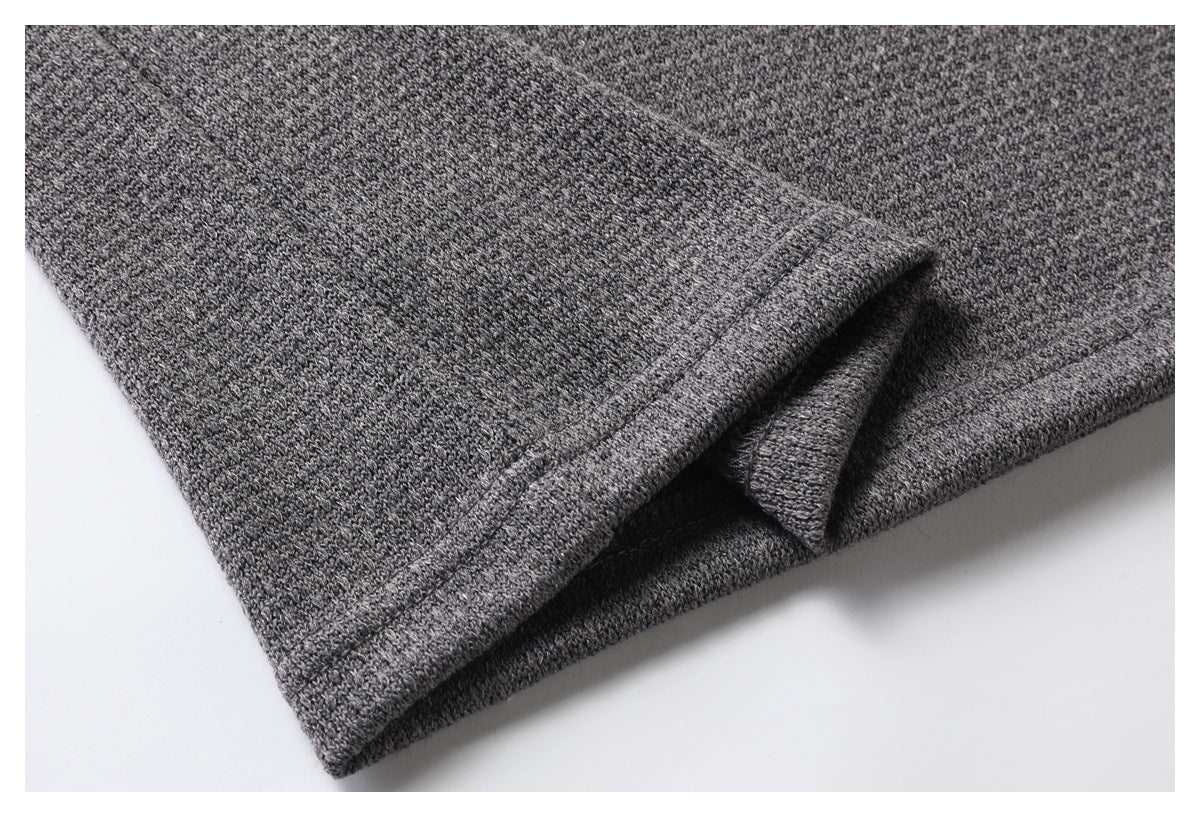 Close-up of a stitched hem on folded gray knit fabric.