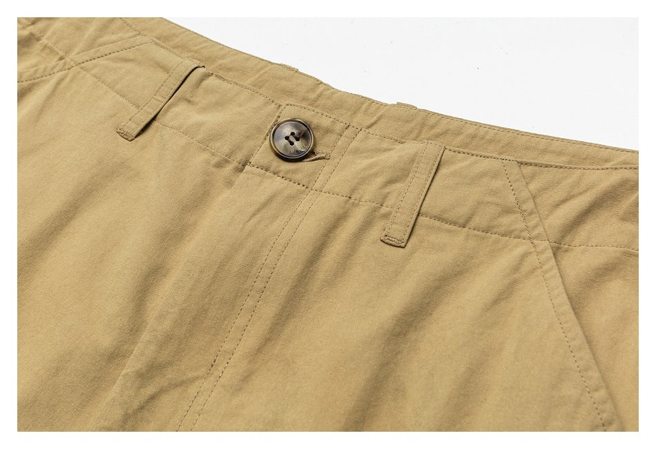Close-up of tan trousers showing the waistband, belt loops, button, and front fly stitching.