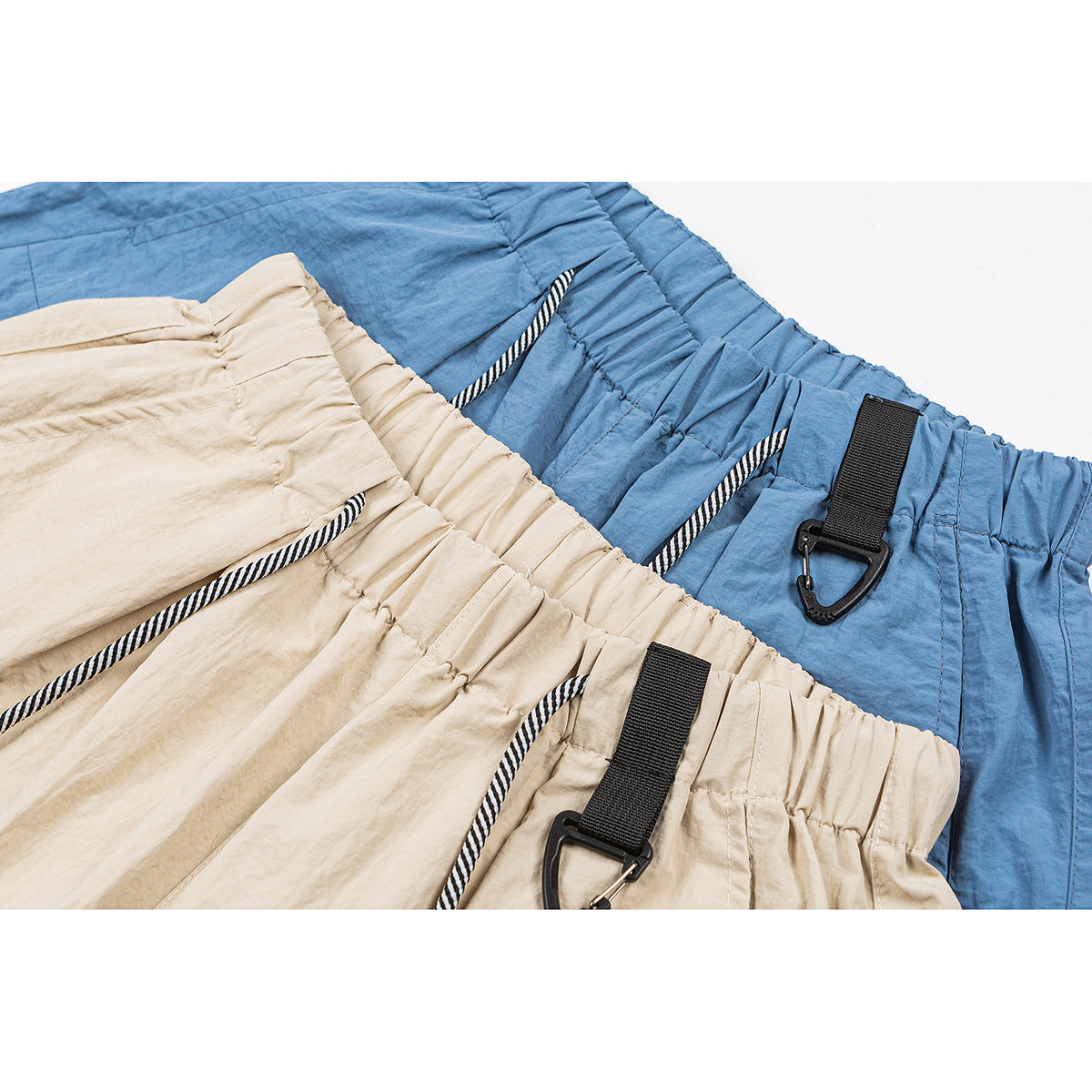Close-up of beige and blue pants waistbands with striped drawcords and black clip straps.