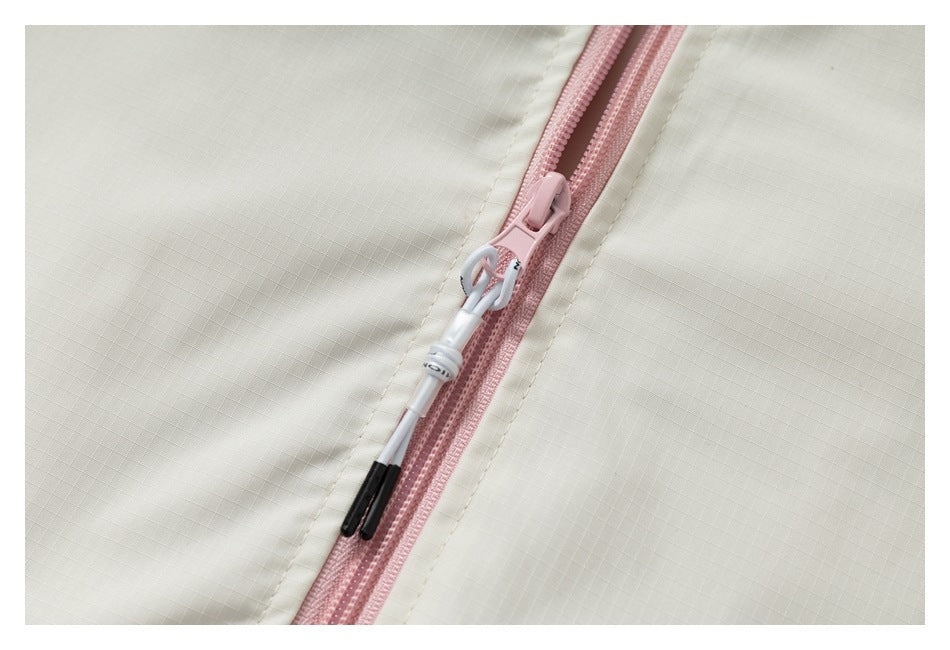Close-up of a pink zipper and white-and-black pull on cream fabric.