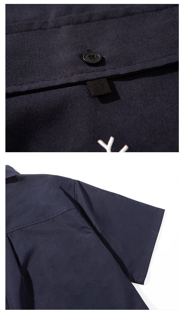 Close-up of the navy shirt's pocket button and white emblem, plus its shoulder seam and short sleeve.