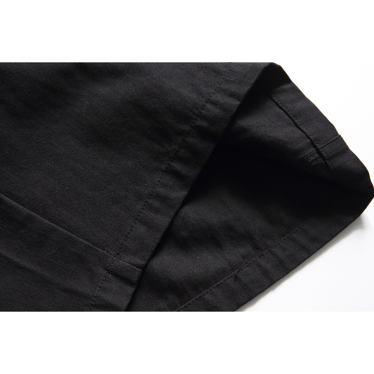 Close-up of a black shorts leg hem and subtle diagonal fabric texture.
