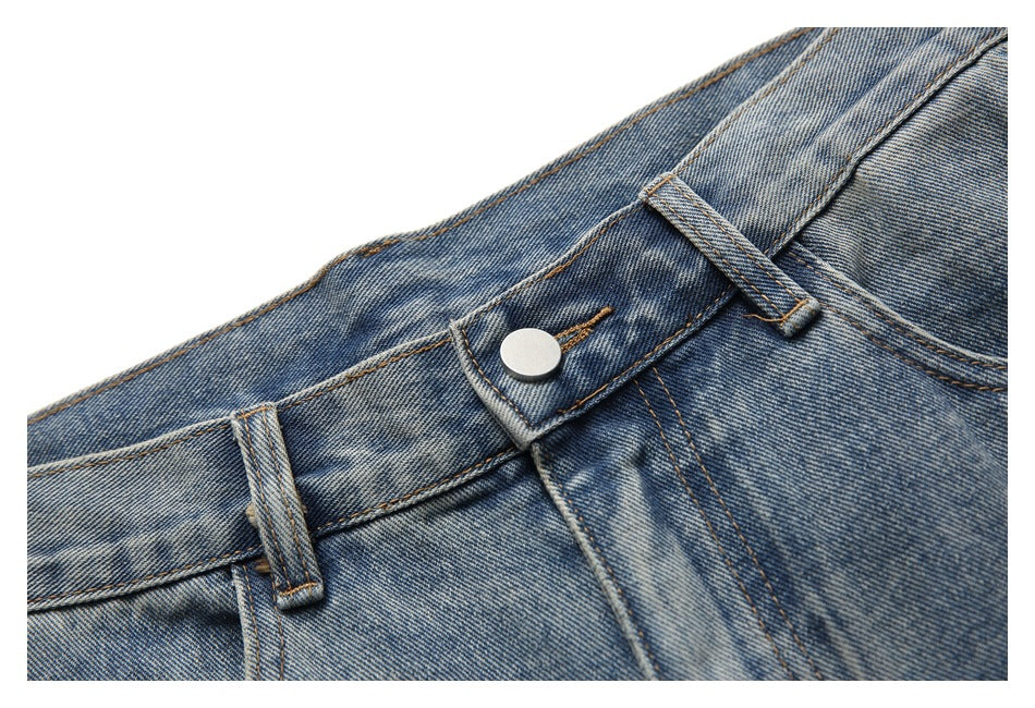 Close-up of the front waistband, belt loops, and silver button on blue washed jeans.