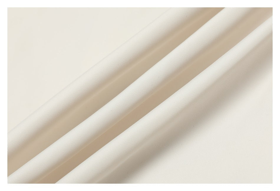 Close-up of ivory fabric arranged in diagonal folds, showing a fine woven texture.