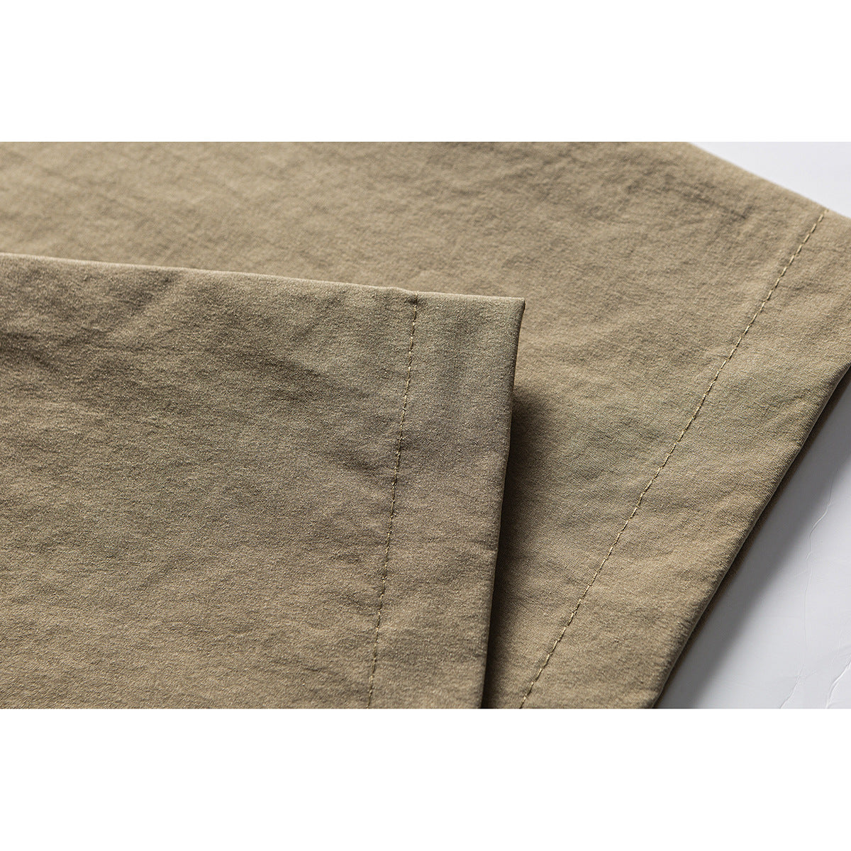 Close-up of layered khaki fabric panels and visible seam stitching.