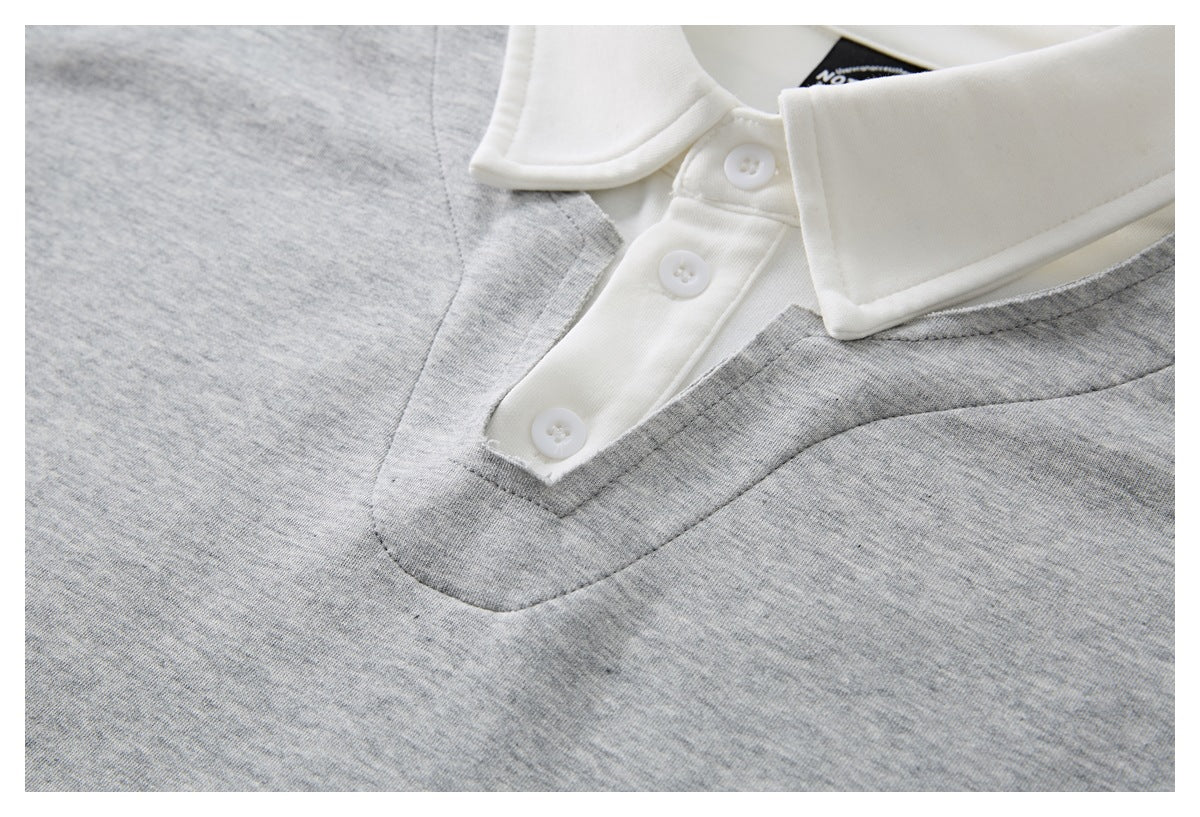 Close-up of the white three-button placket and collar against heather gray polo fabric.