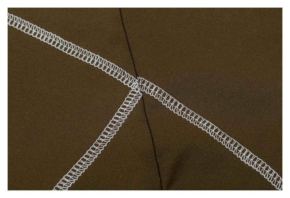Close-up of olive fabric with intersecting white overlock seams and a central folded seam.