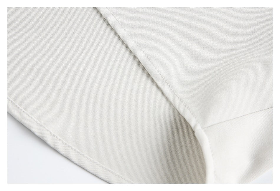 Close-up of a stitched seam and folded edge on light ivory garment fabric.