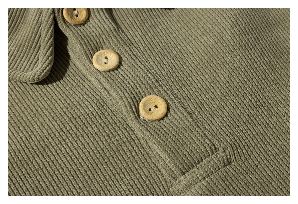 Close-up of three tan buttons on the front of an olive ribbed garment.