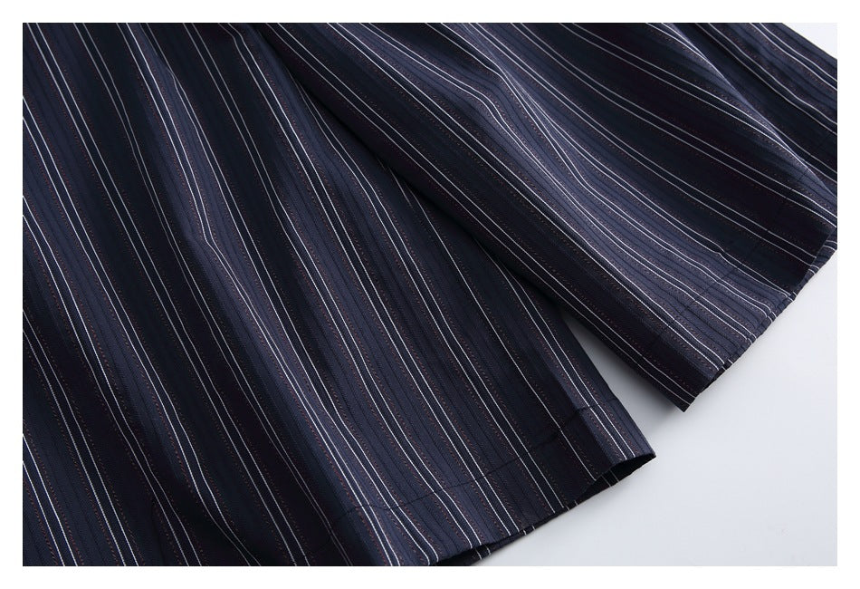 Close-up of the finished hem and drape of dark navy striped garment fabric.