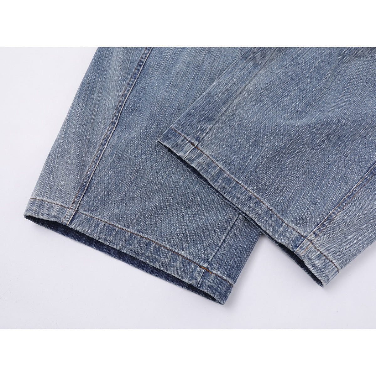 Close-up of the hems of faded blue jeans, showing the wide legs and contrast stitching.