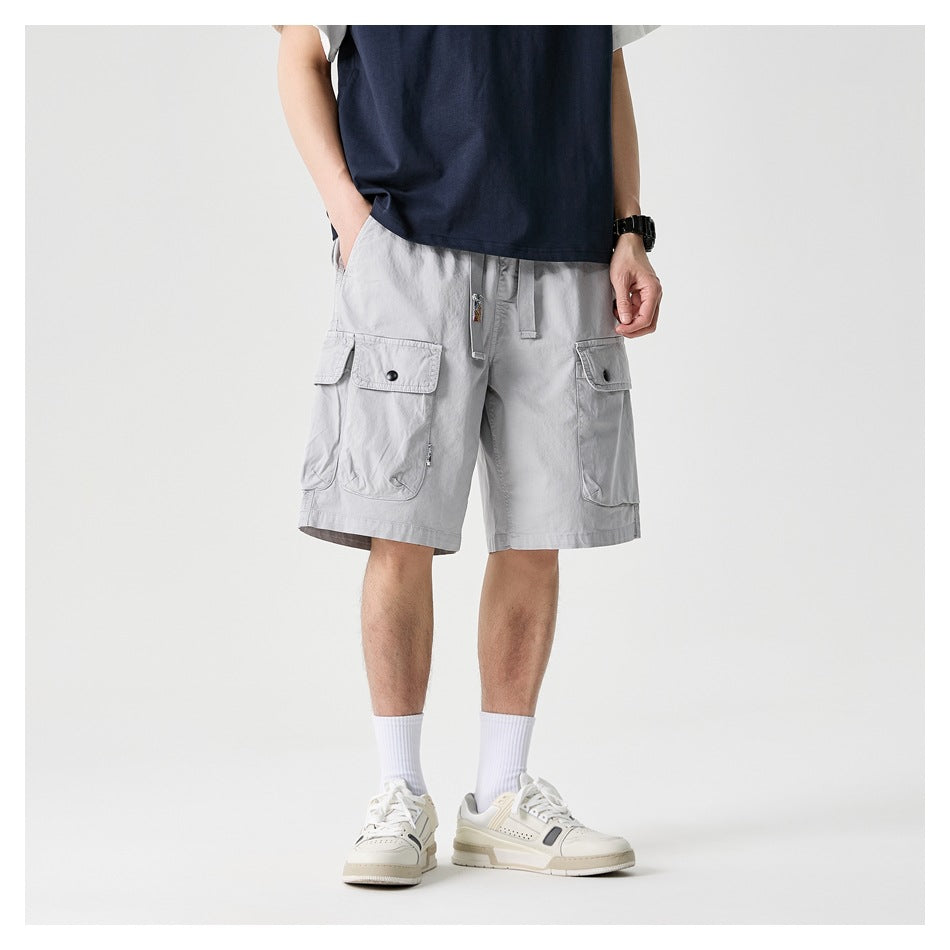 Front view of light gray cargo shorts with drawstring and flap pockets, worn with a navy shirt.