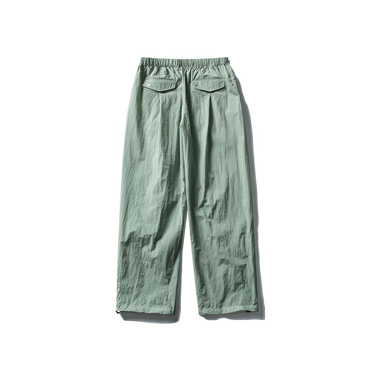 Pale sage green wide-leg pants with an elastic waist and two flap back pockets, shown from behind.